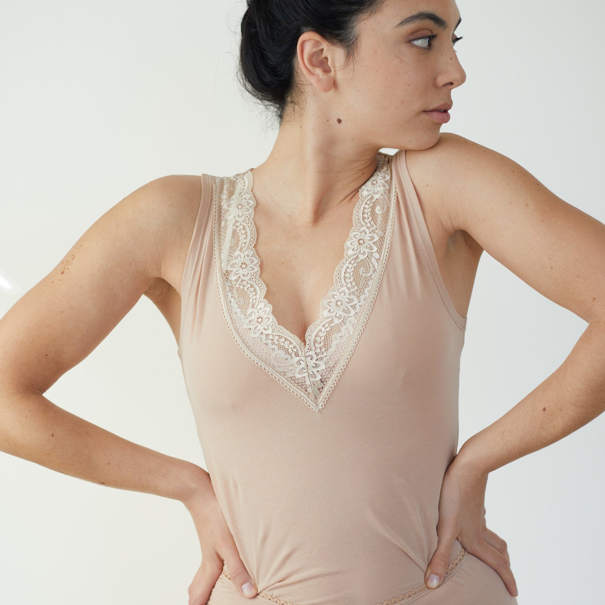 A woman wearing a beige lace-trimmed nightgown with a deep V-neckline.