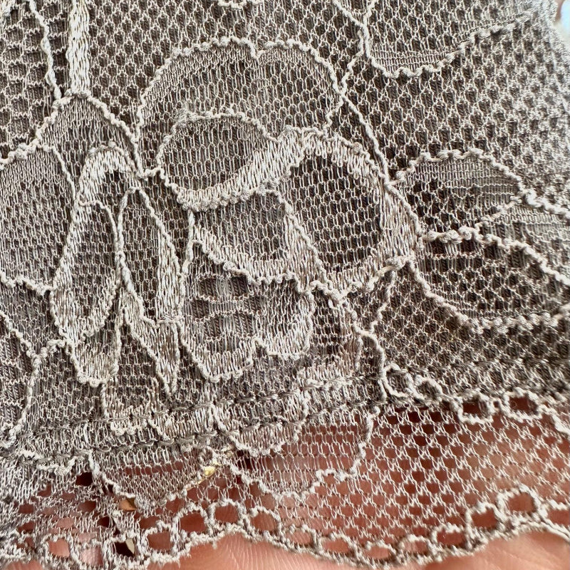 Close-up of intricate lace fabric held between fingers
