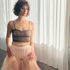 Woman wearing a sheer top and tulle skirt in front of white curtains.
