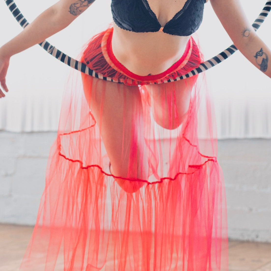 Person wearing a red tulle skirt and black bralette in a casual setting.