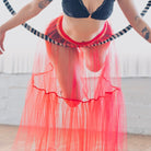 Person wearing a red tulle skirt and black bralette in a casual setting.